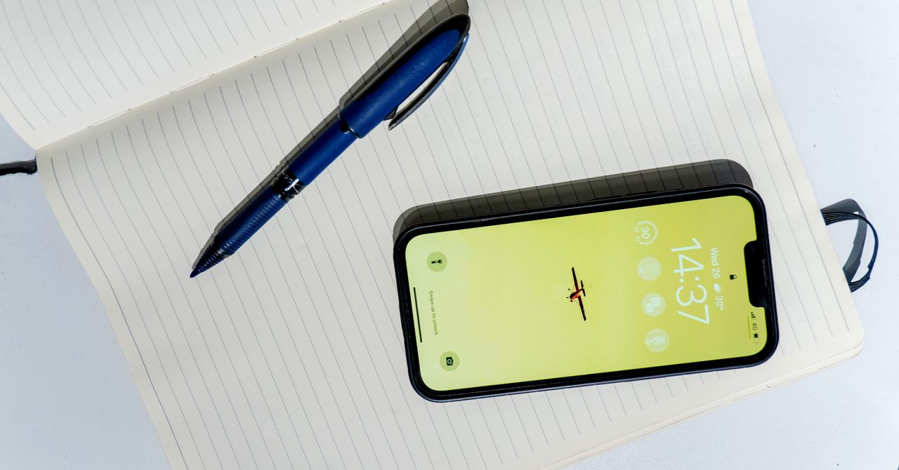 スマートフォンとペンが開いたノートの上に置かれた実写写真